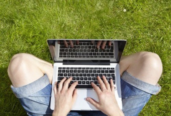 14597553-man-using-laptop-on-a-summers-day-sitting-outside-on-grass